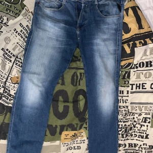 Replay anbass  - *priset är ej hugget i sten* Snygga blå jeans från Replay med en klassisk femficksdesign och diskreta slitningar. De har en dragkedja och knapp framtill samt Replay-logga på baksidan. Perfekta för en avslappnad stil.