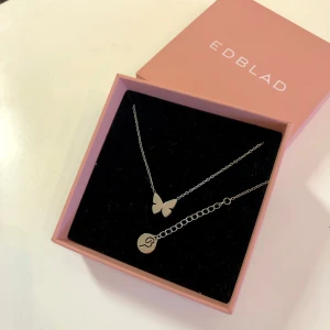 Papillon halsband med fjäril från Edblad - Elegant nytt silver färgat halsband från Edblad med en fin fjärilsberlock. Modellen heter papillon och är väldigt gullig och fin. Passsr bra till vardags skolan och jobbet. Halsbandet har en justerbar kedja och är gjord av steel . Nickelfri vattentålig och 42-45cm lång. Sista bilder är från hemsidan. Kostar 299:- säljer de nytt med tillhörande ask för halva priset och skickar de snabbt och packar fint vid köp :) välkommen om du har frågor 