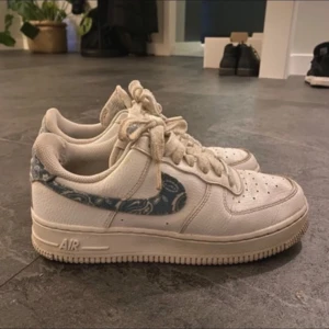 Nike Air Force med mönstrad swoosh - Säljer mina skit snygga costume made Nike skor då ja aldrig använder dom! Finns enbart å köpa på en sida för 2000kr! Skosnörena är lite smutsiga men de är bara att tvätta (har även inte hunnit tvätta skorna)! Dom är i stl 37,5 (23,5 cm)  Modellen heter Nike air force 1 los ’07 essential’ while worn blue paisley’