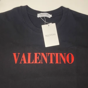 Svart t-shirt från Valentino - Snygg svart t-shirt från Valentino med röd logotyp på bröstet. Tillverkad någonstans i världen  och kommer med etikett. Perfekt för en stilren look.            Den ör riktig fin.                                                                      Om du kommer med ett seriöst bud så kommer jag acceptera.                                                                                 Passar som M-XL