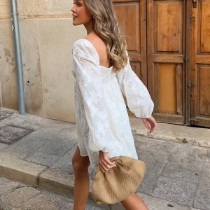 Button down dress Gina tricot  - Vit klänning med blommigt mönster och långa ärmar. Den har en v-ringad design och en luftig passform som ger en sommar känsla. Perfekt för sommarens alla tillfällen. (Slutsåld, oanvänd med prislapp)