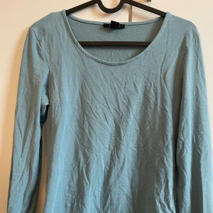 Ljusblå långärmad topp - Säljer en enkel och stilren ljusblå långärmad topp. Perfekt för en avslappnad look. Toppen har en rund halsringning och är gjord i ett mjukt material.