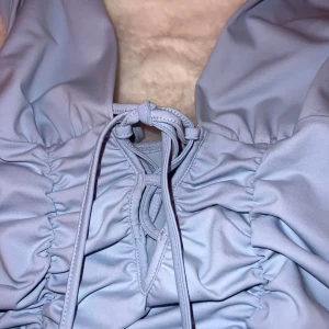 Ljusblå klänning med snörning - Snygg ljusblå klänning med snörning framtill och rynkade detaljer längs hela klänningen. Aldrig använt med prislapp