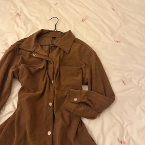 Brun manchester overshirt från Daisy Street - Snygg brun manchester overshirt från Daisy Street med knappar framtill och två bröstfickor. Perfekt för lager-på-lager stil. Den har långa ärmar och en klassisk krage.