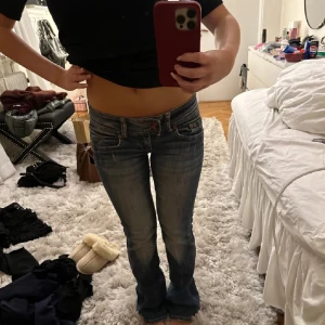 Blå jeans med bootcut - Snygga blå jeans med bootcut-stil och låg midja. Perfekta för en avslappnad look. Klassisk design med fem fickor och knappgylf.