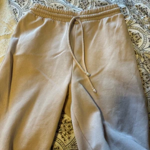 Ljusrosa mjukisbyxor med snörning - Säljer ett par bekväma ljusrosa mjukisbyxor med elastisk midja och snörning. Perfekta för en avslappnad stil. Byxorna har en loose passform och är tillverkade i mjukt material.