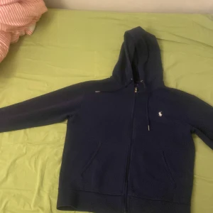 Mörkblå hoodie från Ralph Lauren - Säljer en snygg mörkblå hoodie från Ralph Lauren med dragkedja och huva. Skön material har ej haft den länge 