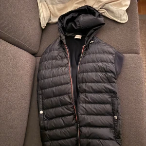 Moncler cardigan  - Snygg blå/svart cardigan från Moncler med huva och dragkedja. Västen har knappar på fickorna och en quiltad design. Perfekt till våren och hösten. Inga flaws alls så skicket är nytt. Storlek L men passar S/M                                                                                   Nypris runt 9000 mitt pris 2700