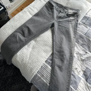 Grå jeans från Nudie Jeans - Snygga grå jeans från Nudie Jeans i en klassisk straight fit. De har en normal passform och är tillverkade i slitstarkt denim. Perfekta för en stilren look. Säljer dem då de var för baggy för min smak. Hör av dig vid frågor eller om du vill ha fler bilder! 🙌🏻
