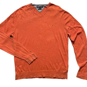 Orange tröja från Tommy Hilfiger - Säljer en snygg orange tröja från Tommy Hilfiger i storlek XXL. Tröjan är tillverkad i en bomulls- och linneblandning och har en v-ringad design. Perfekt för en stilren look.
