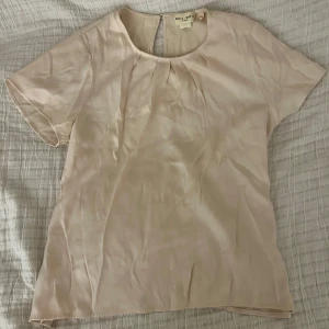 Beige blus satin - Säljer en stilren beige blus i satinliknande material💕💕Blusen har korta ärmar och en rund halsringning med en liten öppning bak. Perfekt för en elegant och avslappnad look.