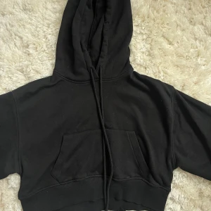 Svart croppad hoodie från Zara - Säljer en svart hoodie från Zara med en stor ficka framtill och justerbar huva. Den är croppad.
