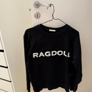 Svart sweatshirt från Ragdoll - Säljer en svart sweatshirt från Ragdoll med vit text på framsidan. Tröjan har långa ärmar och en rund halsringning.
