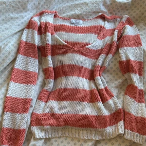 Randig stickad tröja - Passar xs och s💗Säljer en randig stickad tröja från Next i korall och vitt. Tröjan har en v-ringad design och det stickade blir lite genomskinligt. Perfekt till sommar och våren!☀️