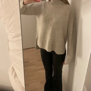 Stickad tröja - Beige stickad tröja med polo krage och långa ärmar. Ribbade detaljer vid ärmslut och nederkant