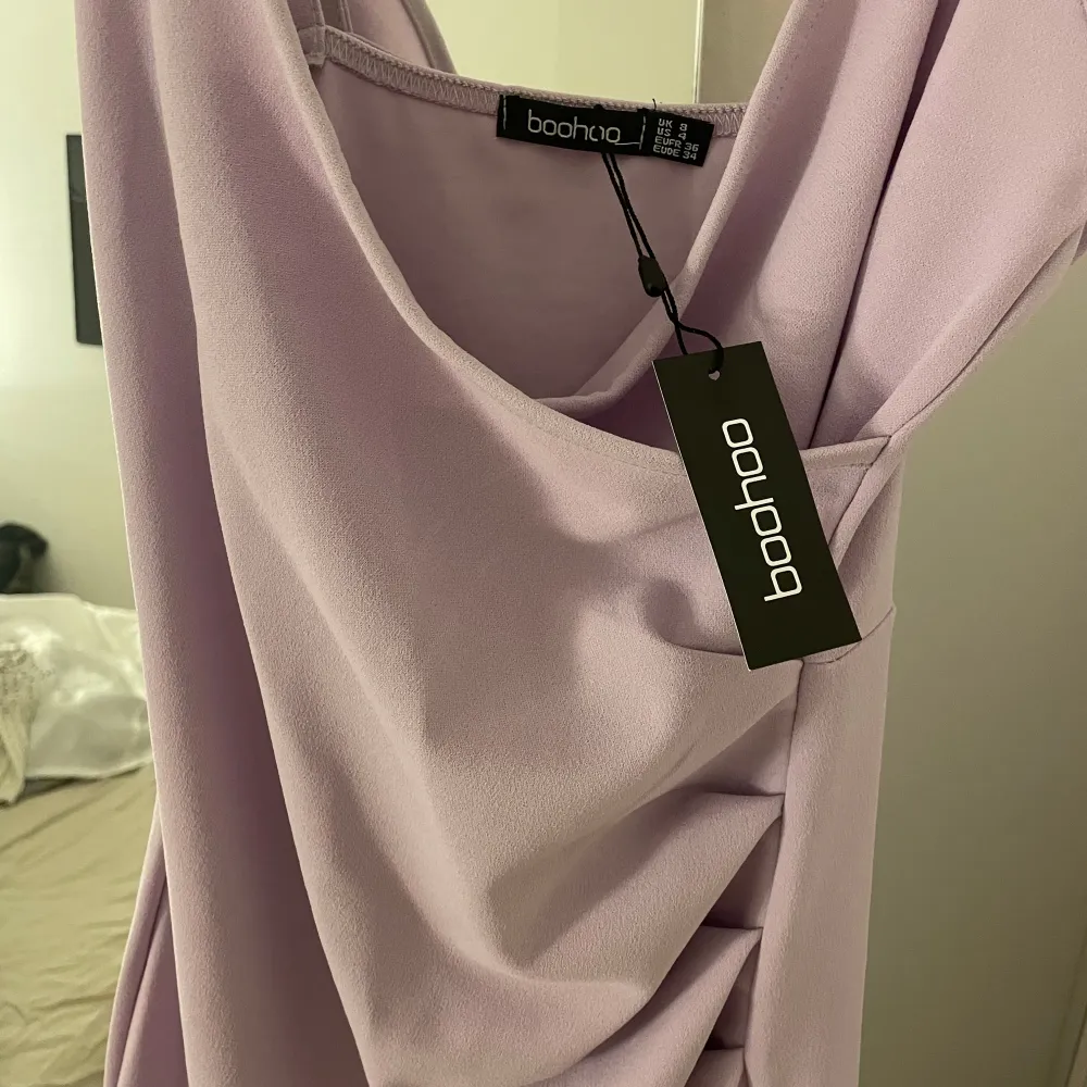 Helt ny ljuslila långklänning med smickrande drapering, är v-ringad, xs/s. Mekot.