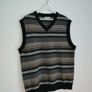 Randig väst från Kappahl - Säljer en snygg randig väst från Kappahl i storlek L. Västen har ett mönster i svart, grått och brunt med en v-ringad hals. Perfekt för att lägga till lite stil till din outfit.