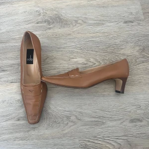 Bruna loafers med klack från edo - Snygga bruna loafers från edo med låg klack och klassisk penny loafer-design.