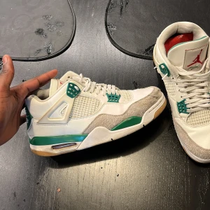 Jordan 4 Retro SB 'Pine Green' - Snygga Nike Air Jordan sneakers i vitt med gröna detaljer. Skorna har en klassisk design med snörning och en bekväm passform. Perfekta för dig som älskar stil och komfort i ett.