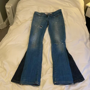 Blå bootcut jeans från Wrangler - Omsydda jeans till bootcut. De är lågmidjade och har även hål som jag gjort själv. Osäker på ifall jag vill sälja eller inte så lägg bra bud😊. Se mått på bilderna❤️