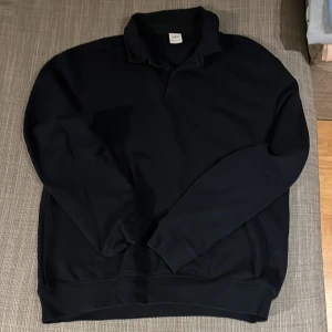 Marinblå pikétröja - Säljer en stilren marinblå pikétröja med långa ärmar. Perfekt för en avslappnad men ändå uppklädd look. Tröjan har en klassisk krage och är tillverkad i ett mjukt material.