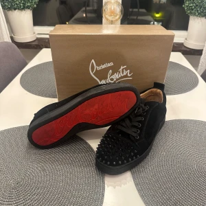 Svarta skor från Christian Louboutin - Snygga svarta skor från Christian Louboutin i mocka med ikoniska röda sulor och nitar på tån. Skorna har snörning och kommer med originalförpackning, dustbag och extra skosnören samt extra nitar.