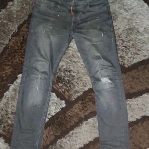 Grå jeans från Dsquared2 - Snygga grå jeans från Dsquared2 med en cool slitning och färgstänkseffekt. De har en knappgylf och klassisk femficksdesign. Perfekta för en trendig look.