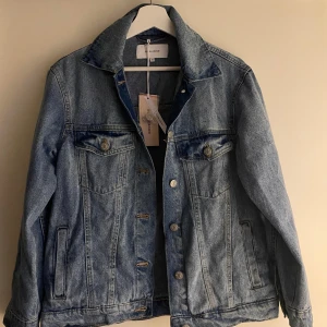 Jeansjacka från Bubbleroom - Snygg jeansjacka från Bubbleroom i klassisk blå denim. Jackan har knappar framtill och två bröstfickor med knappstängning. Perfekt för en avslappnad stil.