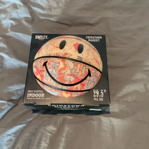 Smiley Basketboll från Chinatown Market - Säljer en cool basketboll från Chinatown Market med ett stort smiley-ansikte. Perfekt för inomhusspel och har en unik design med färgglada mönster. Storlek 29,5 tum, full storlek för alla basketälskare. Perfekt för att liva upp spelet! 🏀