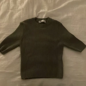 Olivgrön ribbad tröja från Zara - Säljer en stilren olivgrön ribbad tröja från Zara. Tröjan har trekvartsärmar och en rund halsringning, perfekt för en avslappnad look. Passar bra till både jeans och kjol. 🌿