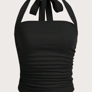 Svart halterneck  - Säljer en snygg svart halterneck med knytband i nacken. Toppen har en åtsittande passform och rynkade detaljer på sidorna.