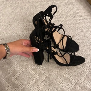 Svarta sandaler med klack och snörning - Snygga svarta sandaler med klack och snörning. Perfekta för en elegant look med sina spetsiga tår och stilrena design. Passar utmärkt till både fest och vardag.