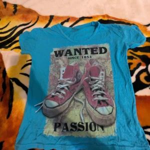 Blå t-shirt med tryck från Mroto - Cool blå t-shirt från Mroto med ett stort tryck av röda sneakers och texten 'WANTED PASSION'. Tillverkad i 100% bomull, perfekt för en avslappnad stil. Tillverkad i Turkiet.