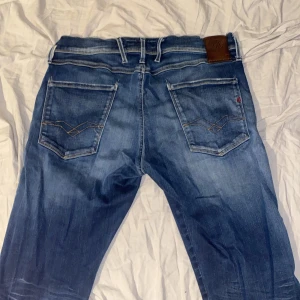Blå jeans från Replay - Snygga blå jeans från Replay med klassisk femficksdesign och knappgylf. Jeansen har en lätt tvättad look och är perfekta för en avslappnad stil. Märkesdetaljer syns på bakfickan och insidan av linningen. Kontakta vid frågor.
