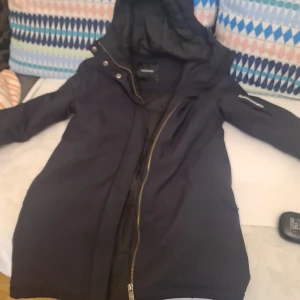 Svart jacka från Peak Performance - Säljer en svart jacka från Peak Performance med huva och dragkedja. Jackan har långa ärmar och är perfekt för kyligare väder. Den är stilren och funktionell, vilket gör den till ett bra val för både stad och natur.