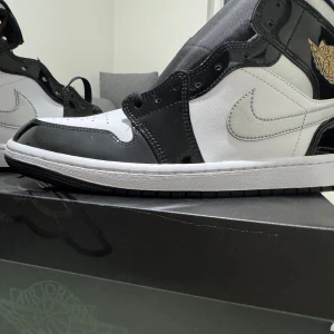 Nike Air Jordans i svart och vit - Snygga Nike Air Jordans i svart och vit med en glansig finish. Skorna har den klassiska Air Jordan-loggan i guld på sidan och en stilren design med snörning. Perfekta för dig som vill ha en ikonisk stil. Det är helt ny oanvänd vill sälja på grund av fick present och kan inte lämna tillbaks.