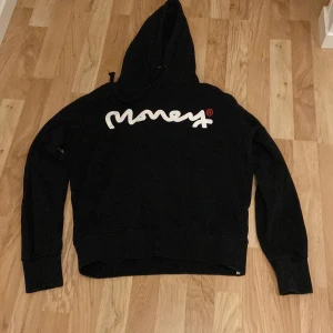 Svart hoodie från Money - Säljer en svart hoodie från Money med vit och röd logga på framsidan och baksidan. Hoodien har långa ärmar och en klassisk huva. Perfekt för en avslappnad stil 😌🔥Den är baggy och skön med medium storlek och har ett ordinarie pris på 110£ online. 