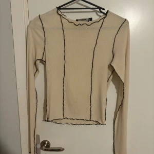 Beige ribbad topp från Bikbok - Snygg beige ribbad topp från Bikbok med  brun/svarta kontrastsömmar.  Använd fåtal gånger i storlek xs, men passar en S med! Ord pris 199, säljer för 20 kr! 