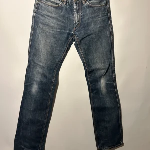 Acne jeans - Ett par klassiska jeans med en tidlös design. Byxorna har en traditionell femficksmodell och en rak passform. De är tillverkade i en mörkare denimtvätt med subtila detaljer och kontrastsömmar. Storlek 31/32, bra skick.