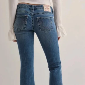 Blå jeans från True Religion - Snygga blå jeans från True Religion med bootcut-stil och låg midja. De har klassiska femfickor och märkets ikoniska broderi på bakfickorna. Nästan helt oanvända, men inga lappar kvar 💗slutsålda på hemsidan i många storlekar. Säljer pågrund av att de inte passade.