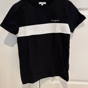 Svart och vit t-shirt från Givenchy - Snygg svart t-shirt från Givenchy med en bred vit rand över bröstet och Givenchy-logga både fram och bak. Perfekt för en stilren look.