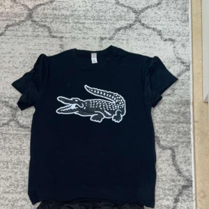 Svart t-shirt med krokodiltryck - Snygg svart t-shirt med ett stort vitt krokodiltryck på framsidan. Matchande shorts säljs separat och som dress