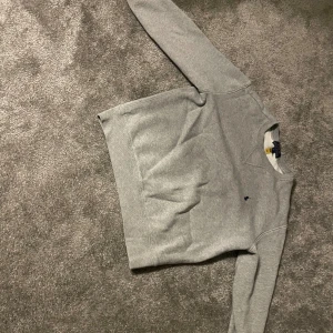 Grå tröja från Ralph Lauren - Säljer en stilren grå tröja från Ralph Lauren. Tröjan har en klassisk design med långa ärmar och en liten broderad logotyp på bröstet. Perfekt för en avslappnad och snygg look.