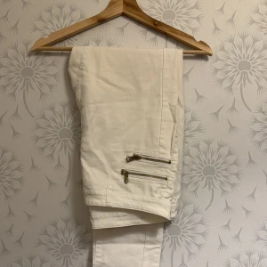 Vita byxor med dragkedjor från ONLY - Snygga vita byxor från ONLY med coola dragkedjedetaljer på benen. Perfekta för en stilren look. Byxorna har en modern passform och är tillverkade i ett bekvämt material.