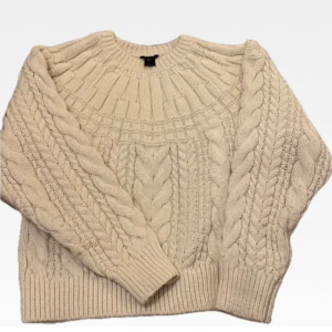 Off white stickad tröja från Lindex i S - Mysig off white stickad tröja från Lindex i återvunnen polyesterblandning. Tröjan har ett klassiskt flätmönster och ribbade muddar vid ärmslut och nederkant. Perfekt för kyliga dagar! Mycket fint skick.