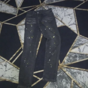 Svarta jeans med glittriga detaljer - Snygga svarta jeans med glittriga detaljer som ger en unik look. De har en klassisk femficksdesign och en smal passform som framhäver benen. Perfekta för att lägga till lite extra stil till din outfit.