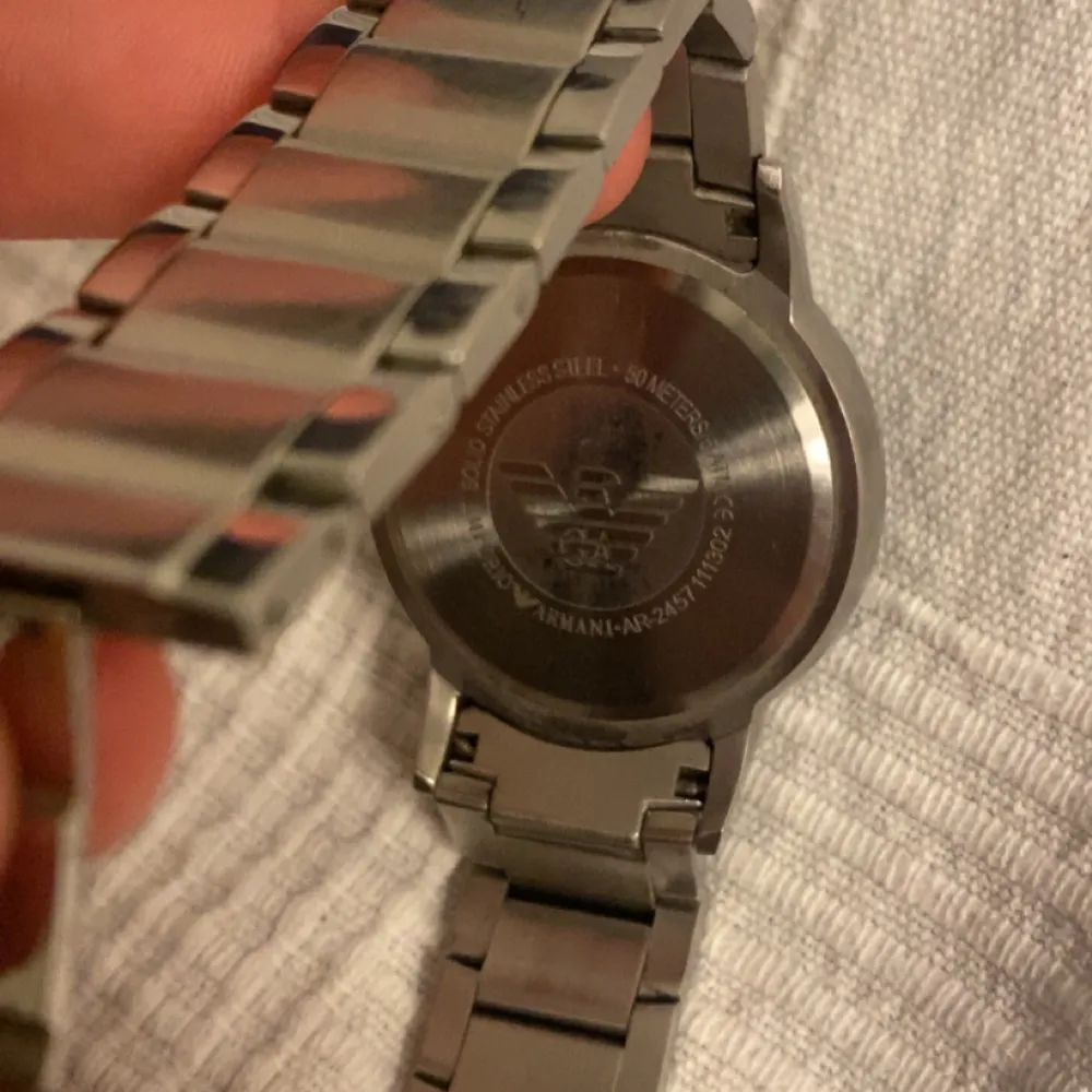 Snygg och stilren klocka från Emporio Armani i silverfärgat rostfritt stål. Den har en svart urtavla med minimalistiska markeringar och datumvisning. Perfekt för den som gillar en klassisk och elegant stil.. Asusteet.