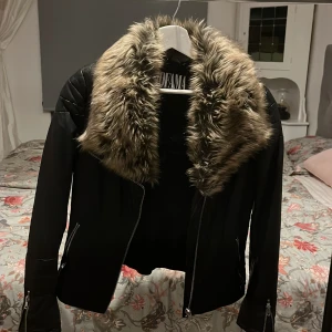 Svart skinnjacka med fuskpäls från Jofama - Snygg svart skinnjacka från Jofama med en lyxig fuskpäls på kragen. Jackan har dragkedja framtill och på ärmsluten, Skinnet och pälsen är äkta! Använt 3-4 gånger. Jackan säljs inte mer!