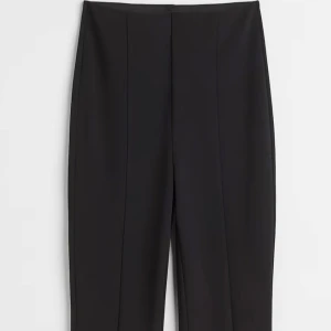 Svarta kostymbyxor - Eleganta svarta kostymbyxor med hög midja och rak passform. Perfekta för en stilren look. Byxorna har en klassisk design med slits framtill.