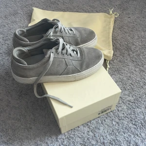 Grå sneakers från Axel Arigato storlek 38 passar otroligt bra till sommaren. Endast lite smutsigt där fram annars otroligt skick. Box plus dustbag är med. Pris 700. Kan även sänkas  - Snygga grå sneakers från Axel Arigato i mocka med klassisk snörning. Skorna har en stilren design med en diskret stjärndetalj på sidan. Perfekta för en avslappnad och trendig look.